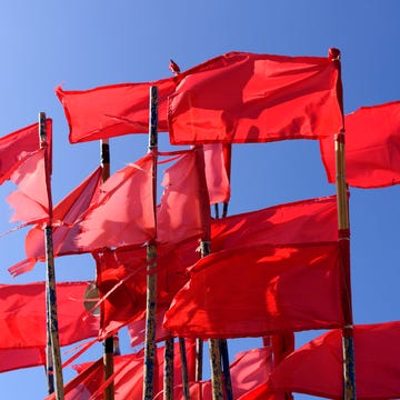 red fishing buoy flags on the boat moored in the dock against the blue sky