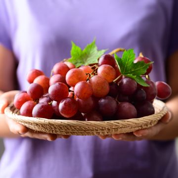 red grapes fruit holding by woman hand