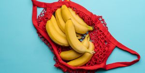 red grocery reusable cloth bag with group of yellow bananas on blue background, pollution free material concept