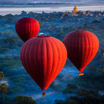 red hot air balloons over jungle, nyaung u, mandalay region, myanmar