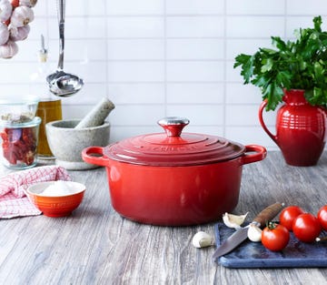 red cast iron cookware with fresh ingredients and kitchen utensils arranged for cooking