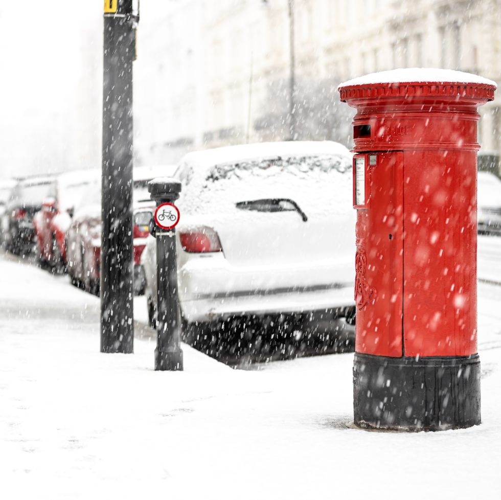 london classic red mailbox  under the falling snow, uk
