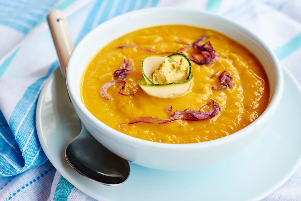 sopa de boniato con cebolla roja, adornada con rodajas de cebolla roja y una rosa de calabacín
