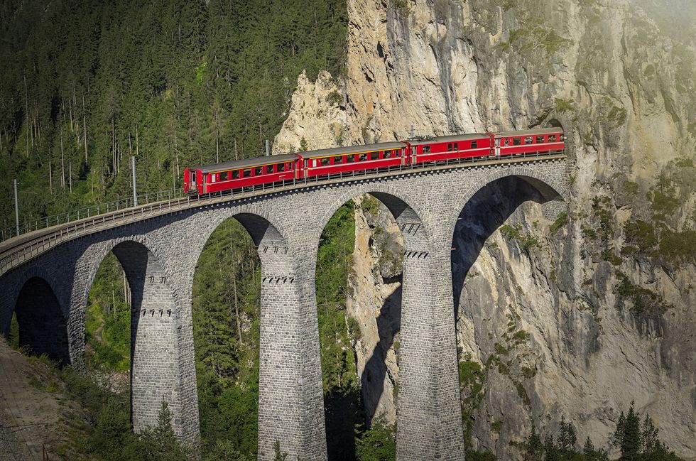 red train over a stone viaduct