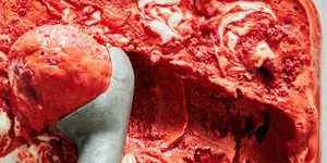 red velvet ice cream with cream cheese swirls topped with red velvet pieces being scooped with an in ice cream scooper