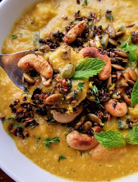 close up of red lentil soup topped with cashews and mint