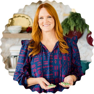 person holding decorated cookies in a kitchen setting