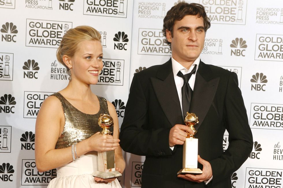 reese witherspoon and joaquin phoenix holding golden globe awards while standing on a red carpet and posing for photos