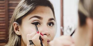 Reflection Of Woman Applying Eyeliner On Mirror