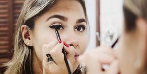 Reflection Of Woman Applying Eyeliner On Mirror