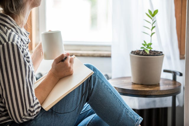 a young woman takes a break to do something analog like writing in her journal and drinking tea this is a healthy practice for those who experience anxiety