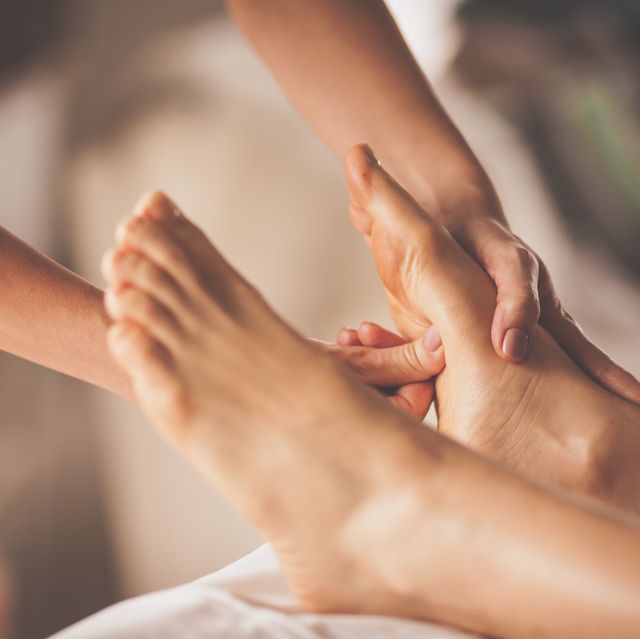 reflexologist applying pressure to foot with thumbs