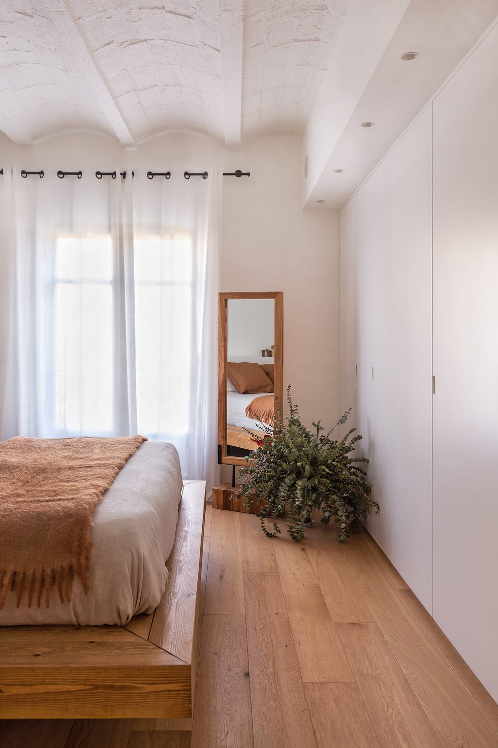 dormitorio con armario empotrado blanco y vigas vistas