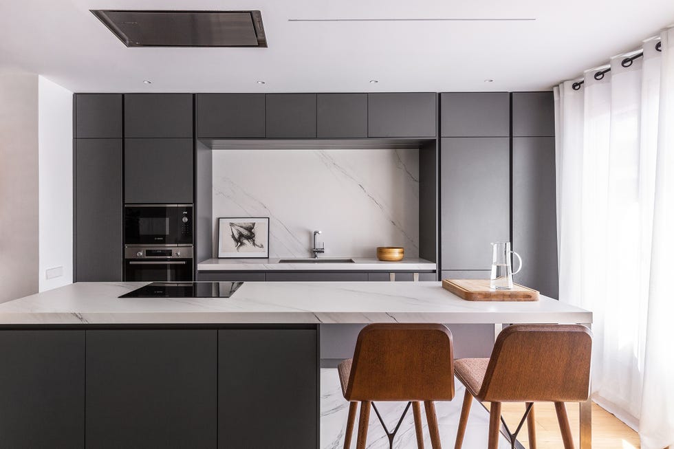 cocina abierta moderna con isla central, encimera de mármol y puertas sin tiradores de color gris y acabado mate
