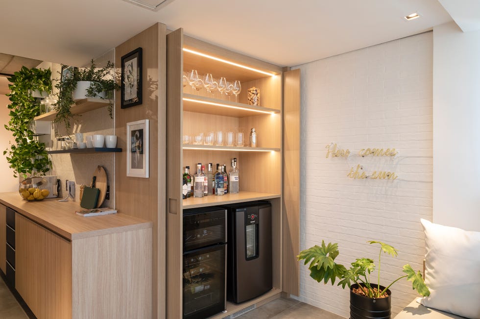 bar oculto dentro de un armario de madera y pared de ladrillos pintados de blanco