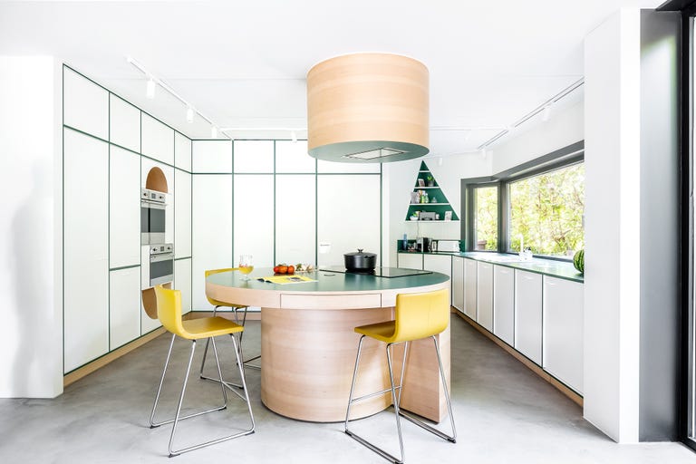 cocina moderna diseñada en blanco con juntas verdes y una isla central de madera que actúa como mesa de comedor