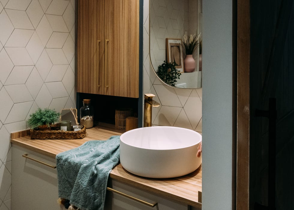 baño con azulejos geométricos y encimera de madera