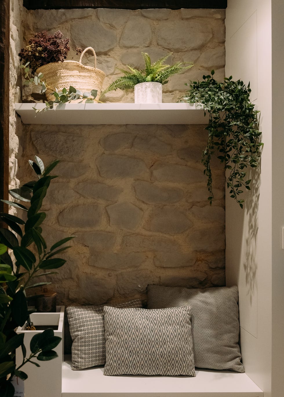 banco diseñado a medida con cojines y pared de piedra