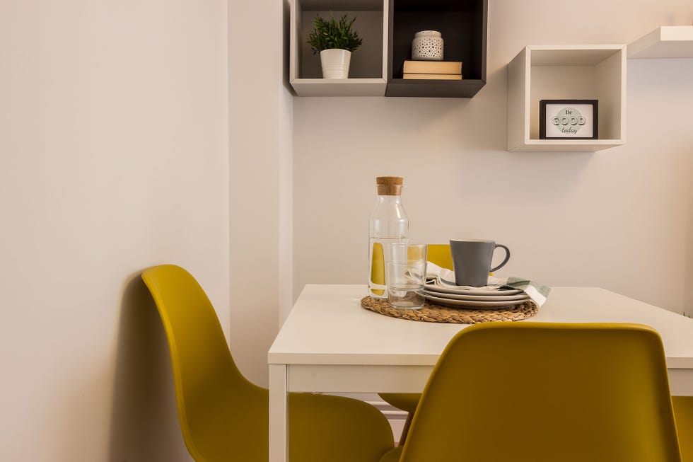 mesa de comedor blanca de estilo nórdico y sillas mostaza