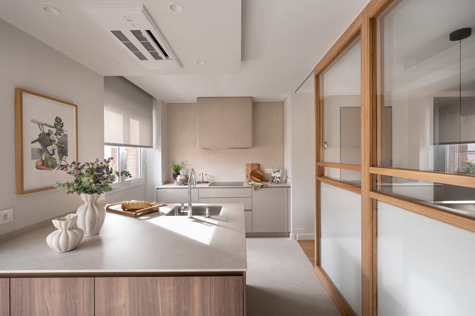 cocina con península y cerramiento de cristal con perfilería de madera