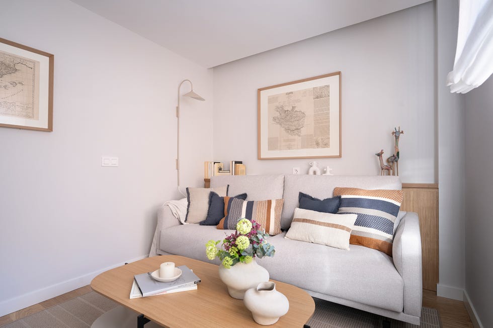 salón con sofá gris y mesa de centro ovalada con sobre de madera
