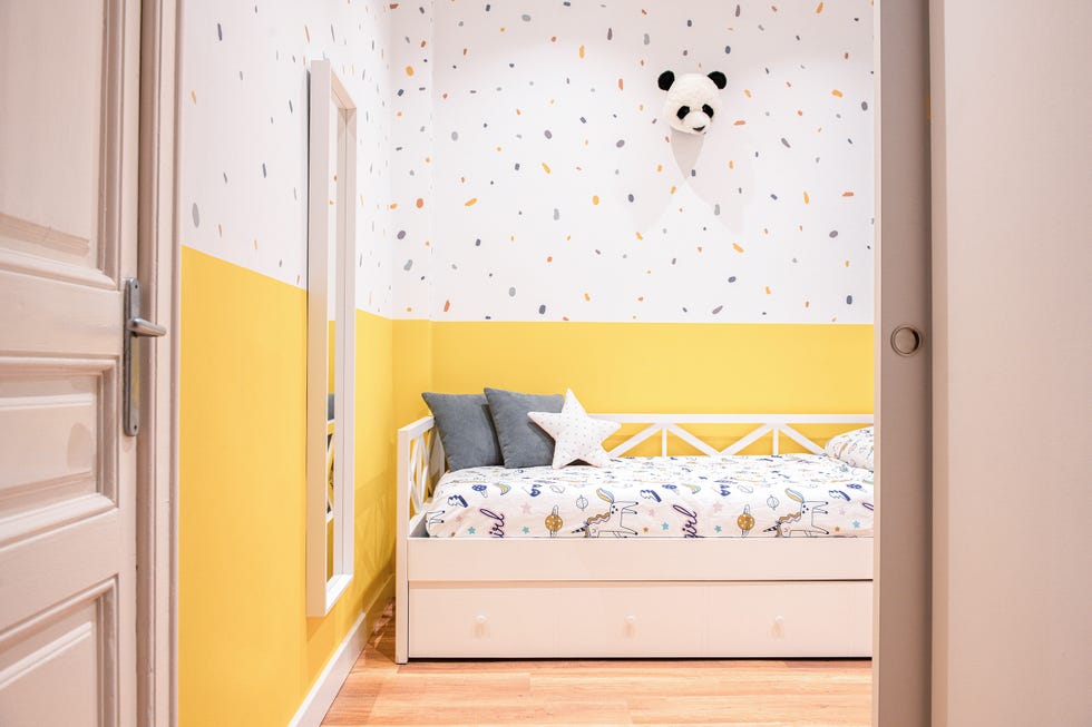 habitación infantil con cama nido blanca y pared de color amarillo con papel pintado