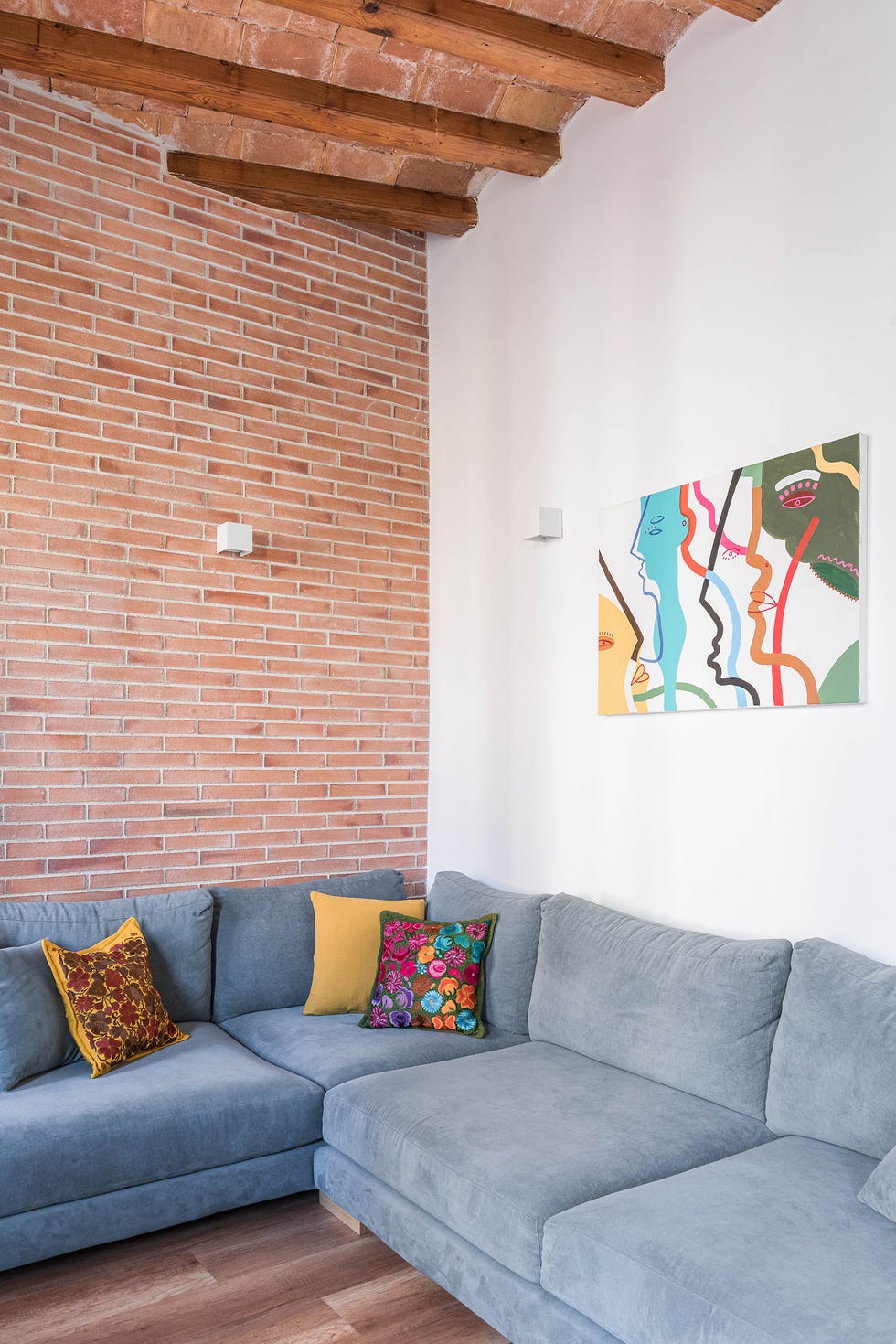 salón con pared de ladrillo visto y sofá esquinero gris