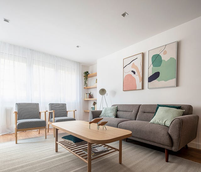 salón de estilo contemporáneo con sofá y butacas grises y mesa de centro de madera
