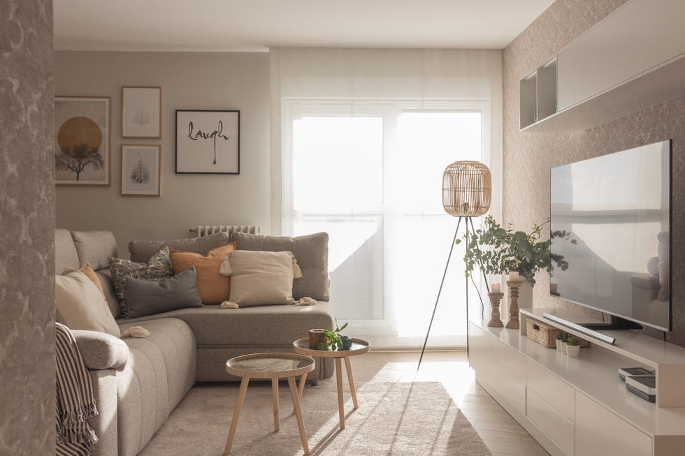 salón decorado en tonos neutros con sofá con chaise longue gris y mesas nido redondas