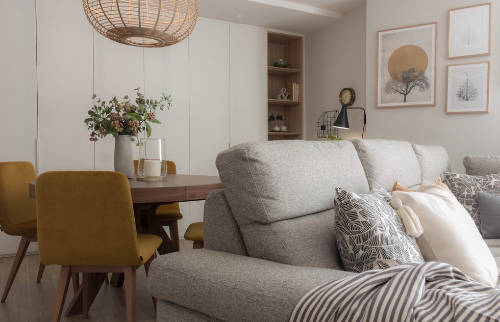 salón comedor de diseño moderno con sofá gris, mesa de comedor redonda y sillas en color mostaza