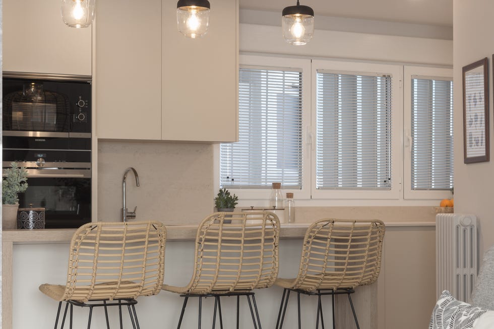 cocina abierta al salón con barra y tres taburetes
