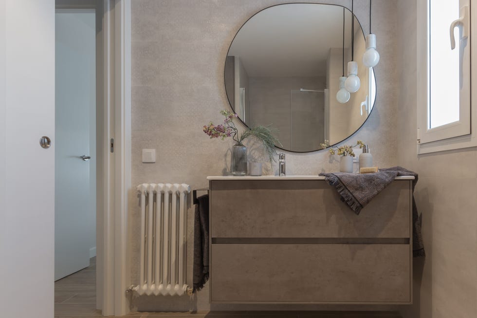 baño con azulejos cerámicos con textura, mueble bajolavabo suspendido y espejo con forma orgánica
