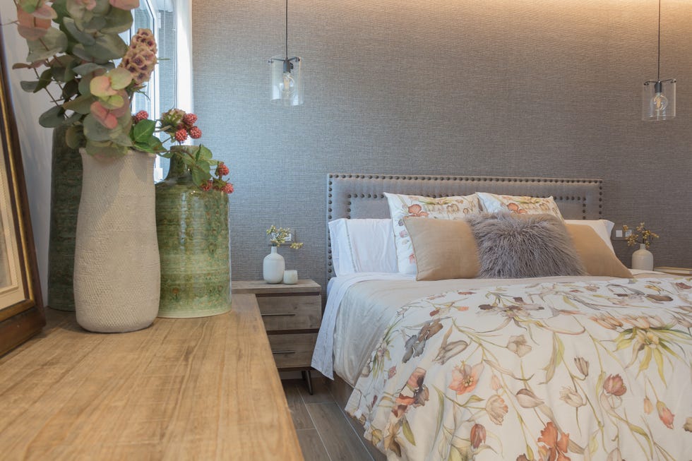 dormitorio con papel pintado efecto tejido y cabecero con remaches decorativos