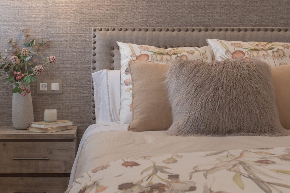 dormitorio con papel pintado efecto tejido y cabecero con remaches decorativos