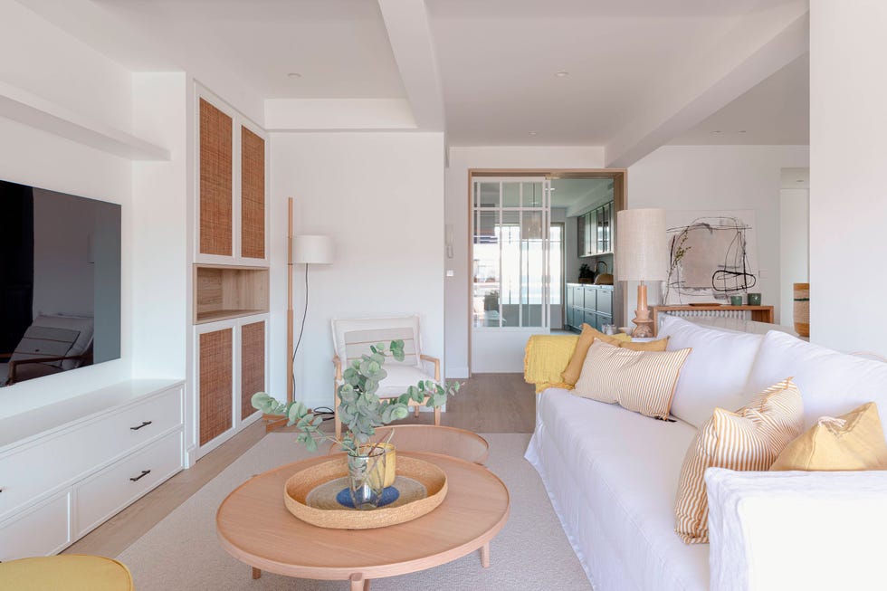 salón con sofá de lino, mesas de centro tipo nido de madera y mueble de tv blanco junto a armario con puertas de cannage
