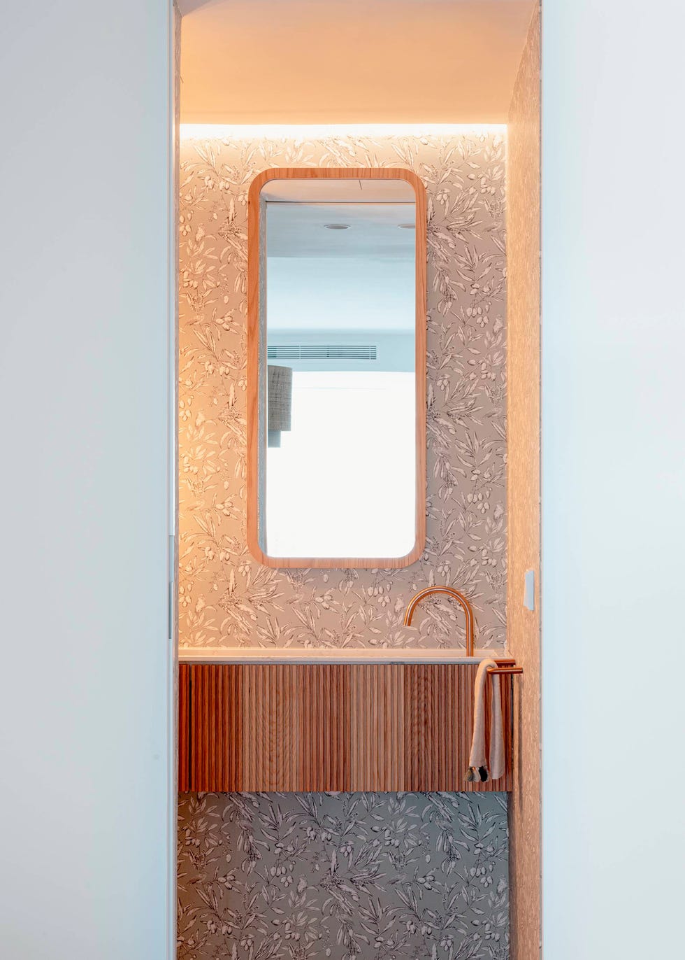 baño con mueble volado con frente acanalado y papel pintado con motivos florales