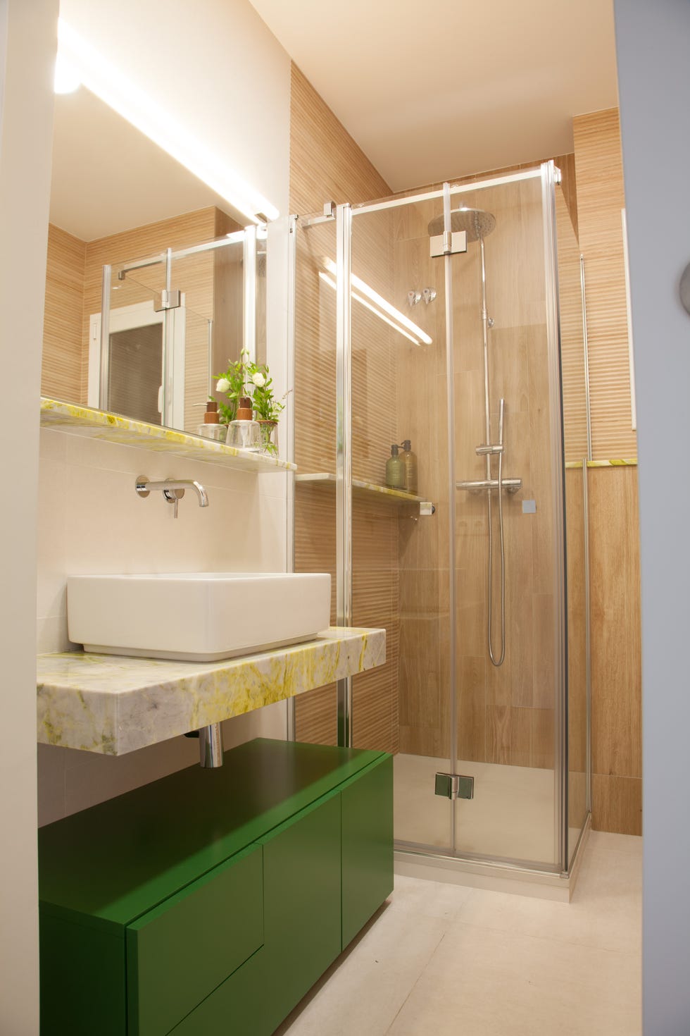 baño con cabina de ducha y mueble de lavabo verde con repisa de granito