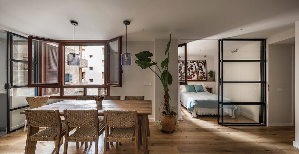 comedor con mesa de madera y sillas de fibras abierto al dormitorio