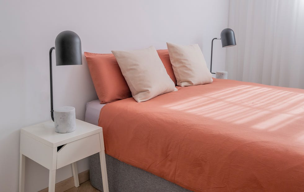 Dormitorio decorado en tonos neutros con ropa de cama naranja empolvado