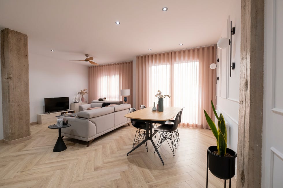 Salón-comedor con pilares de hormigón decorado en tonos dulces y suelo de espiga