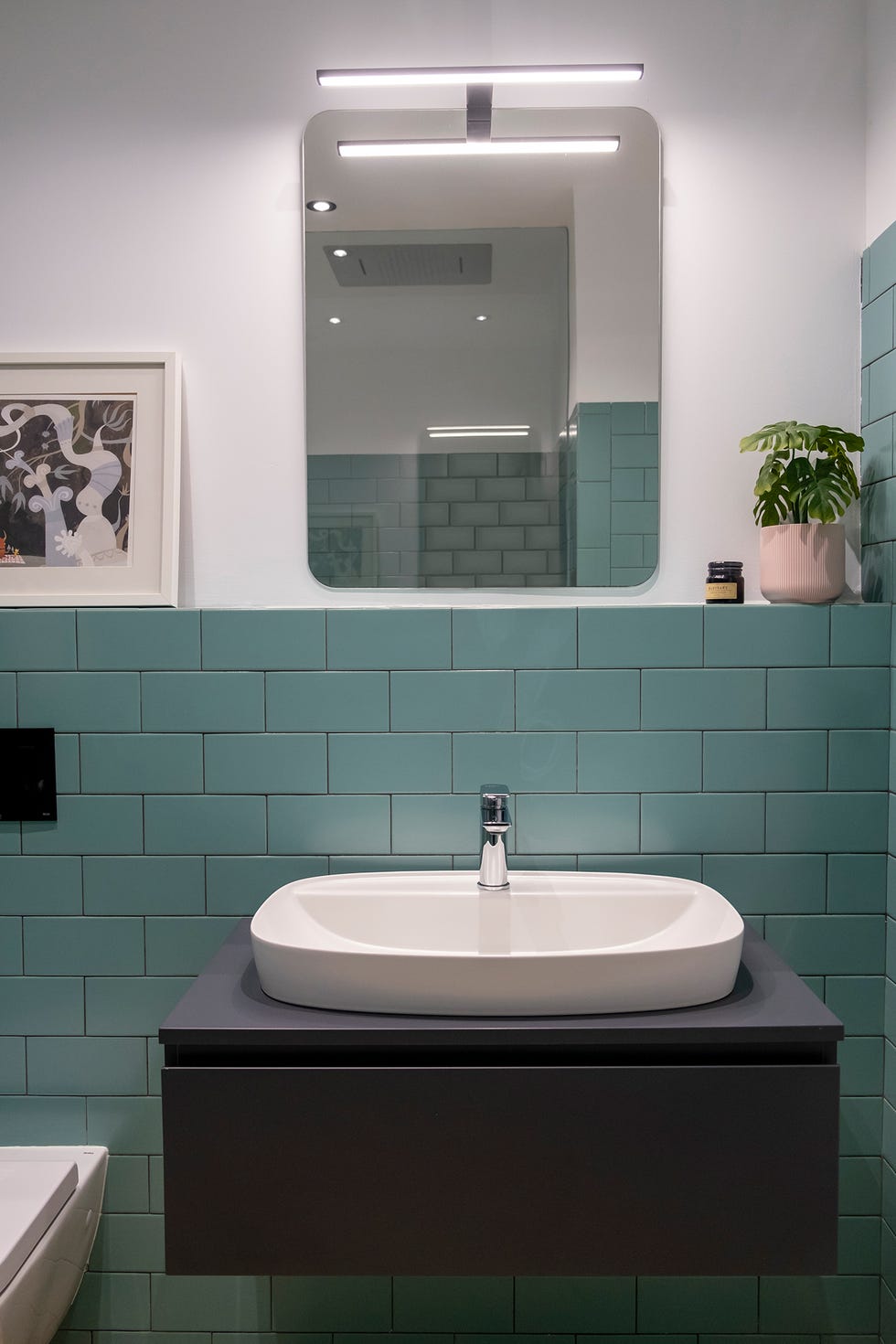 Baño decorado con pequeñas baldosas verdes biseladas y un rejunte gris