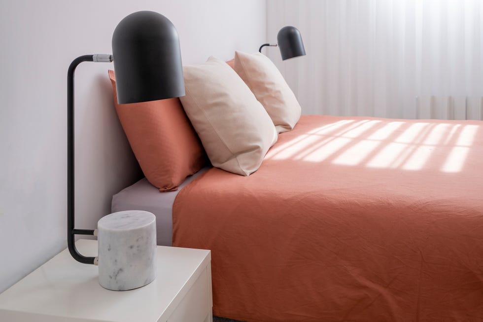 Dormitorio decorado en tonos neutros con ropa de cama naranja empolvado