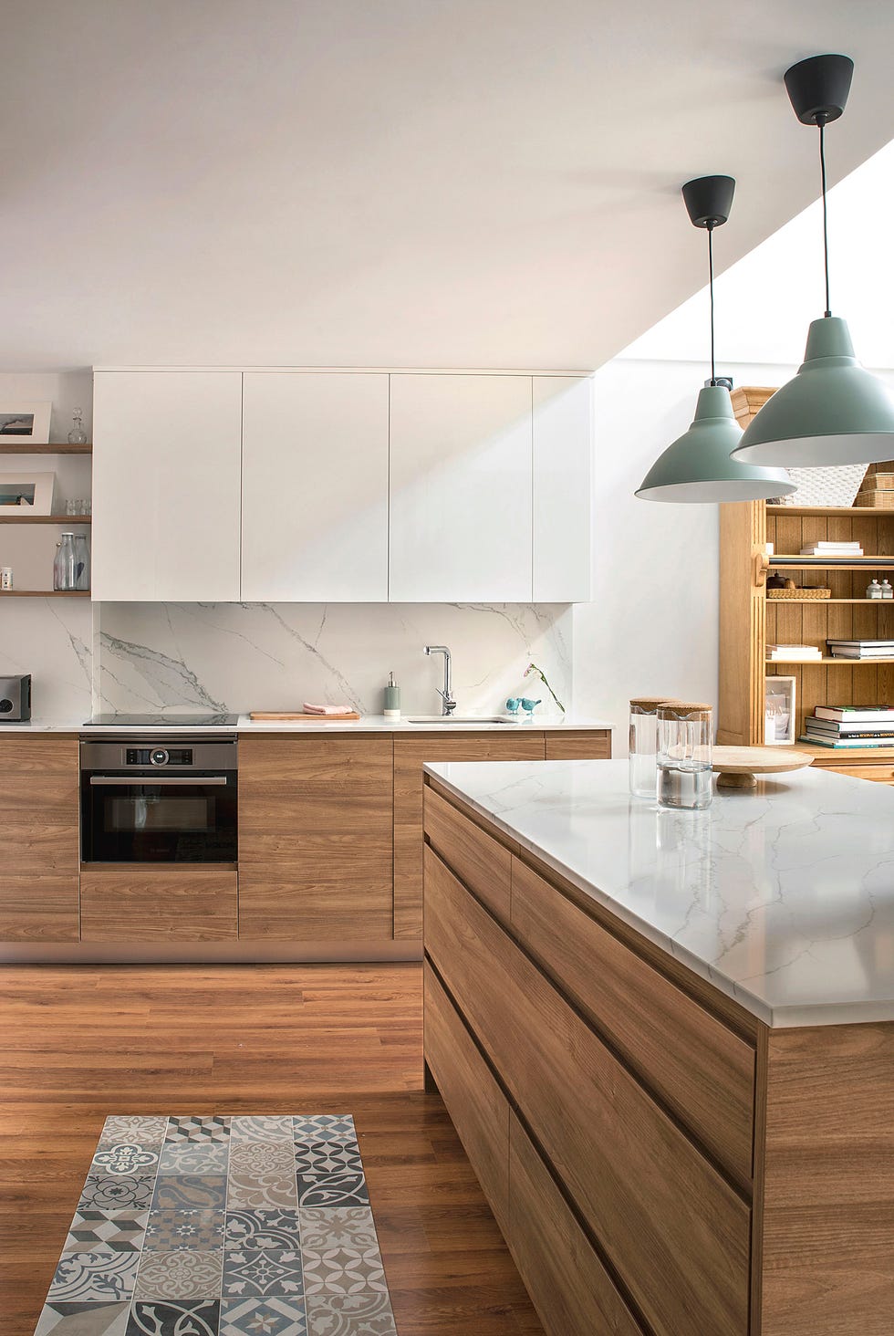 cocina con isla central, revestimientos efecto mármol y armarios de madera sin tiradores