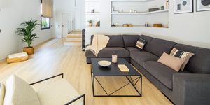 salón abierto moderno con sofá rinconera gris y estantería de obra