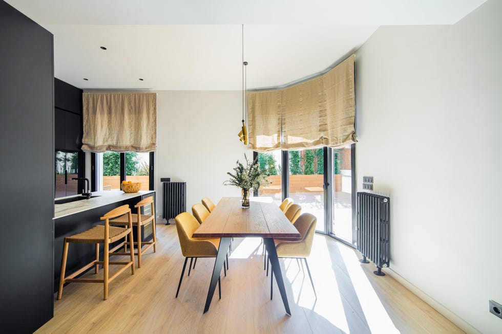 mesa de comedor de madera con patas de acero y sillas de terciopelo mostaza