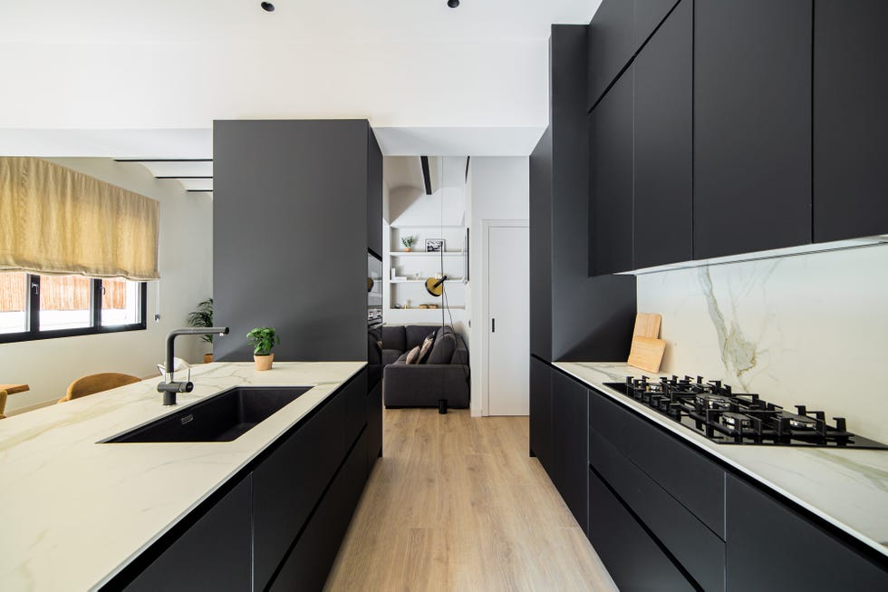 cocina abierta al salón con armarios negros con acabado mate y encimeras de mármol