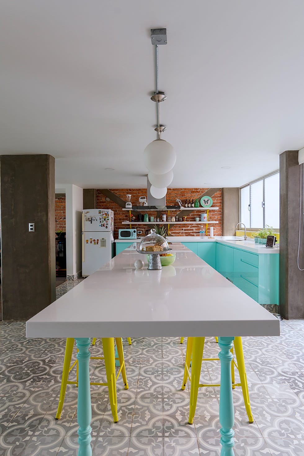cocina con armarios azul turquesa y barra de desayunos blanca con taburetes