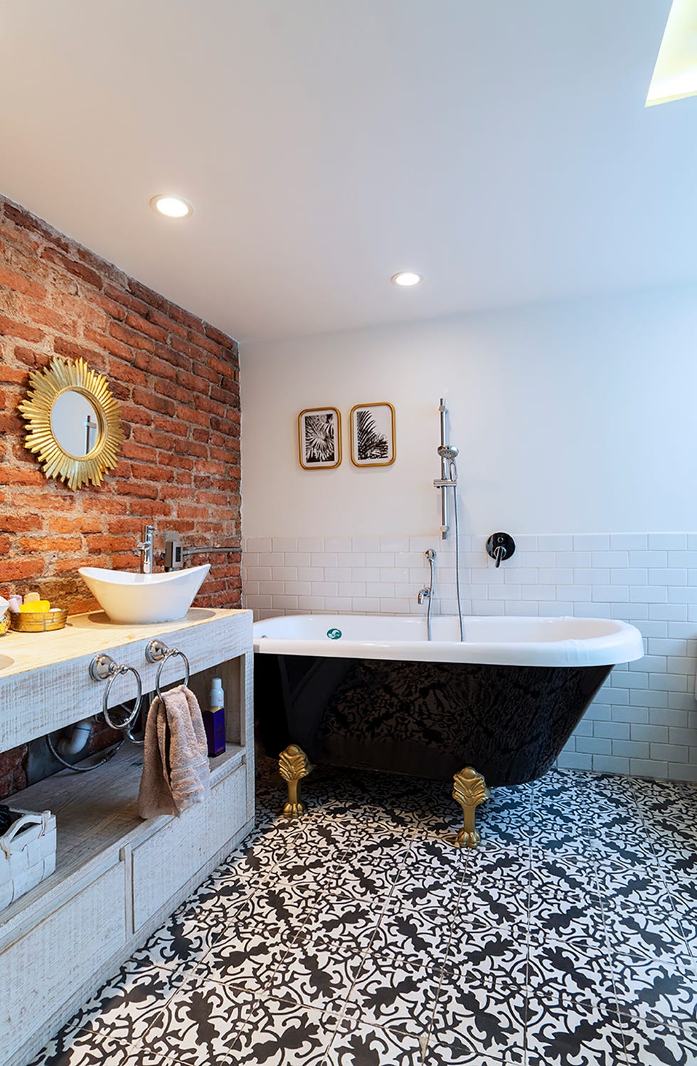 baño de diseño industrial con pared de ladrillo visto y bañera vintage negra