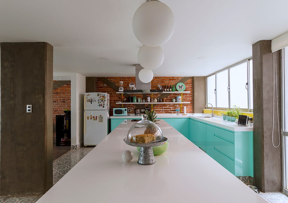 cocina con armarios azul turquesa y barra de desayunos blanca con taburetes