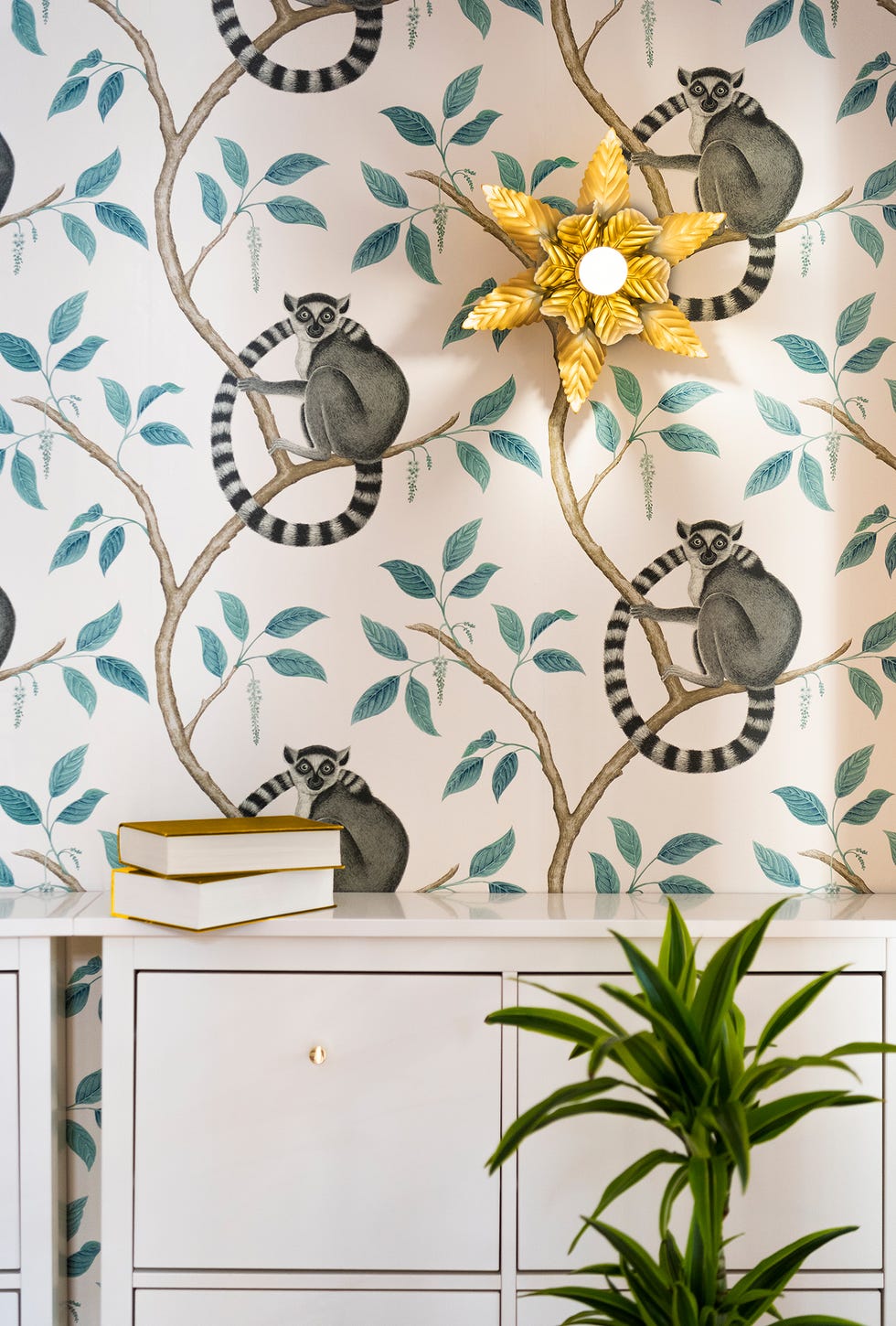 recibidor con mueble zapatero blanco, papel pintado con lémures, y aplique dorado con forma de palmera